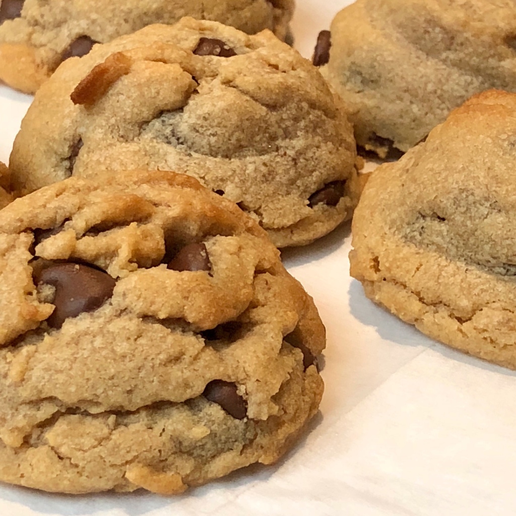A close-up image of several cookies, rounded in shape and each displaying several chocolate chips 