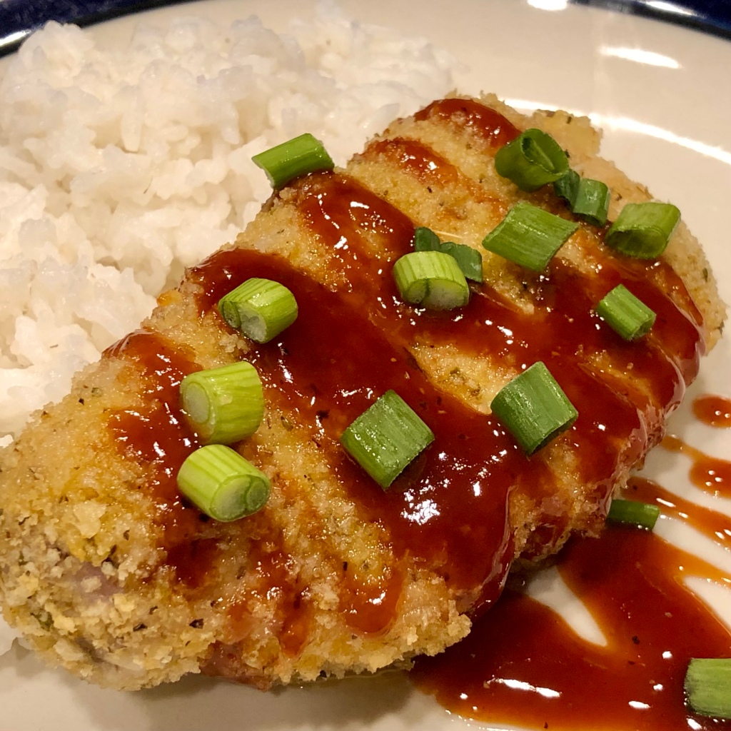 Oven-Fried Tonkatsu: a breaded pork cutlet, drizzled with a deep red sauce and garnished with green onions, served over white rice  